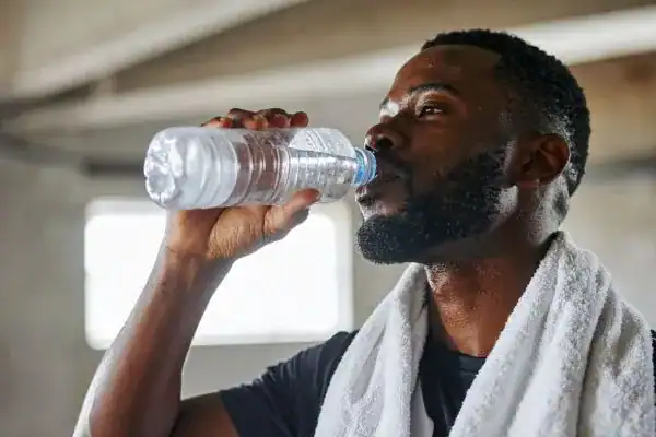 Image of man drinking water to improve hydration Northwich after work out.
